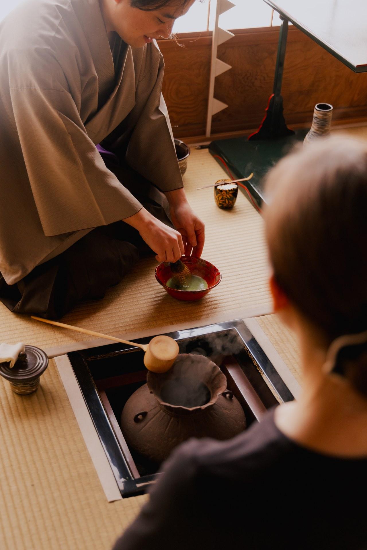 Tea master whisking matcha in a red bowl